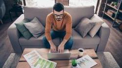 Young male entrepreneur reviewing finance reports in home space